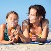 mother and daughter blowing bubbles on the beach